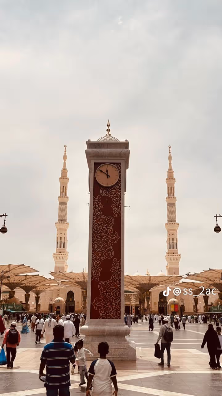 Clock tower in the Prophet's Mosque plaza with minarets and worshippers